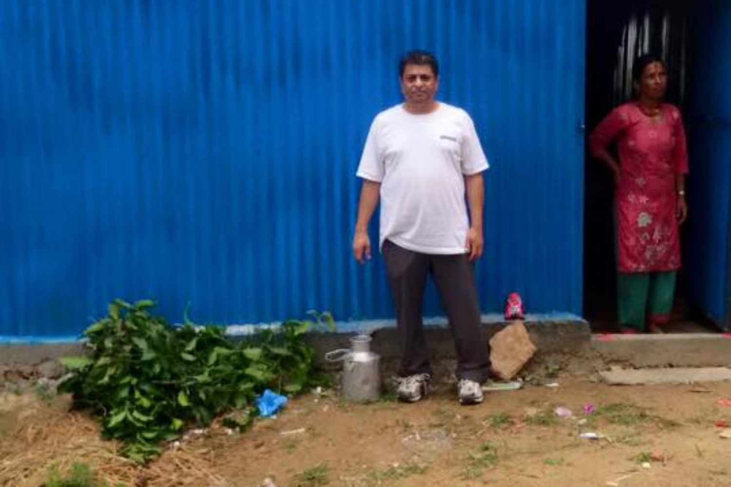 Indian man and woman standing in front of their blue home