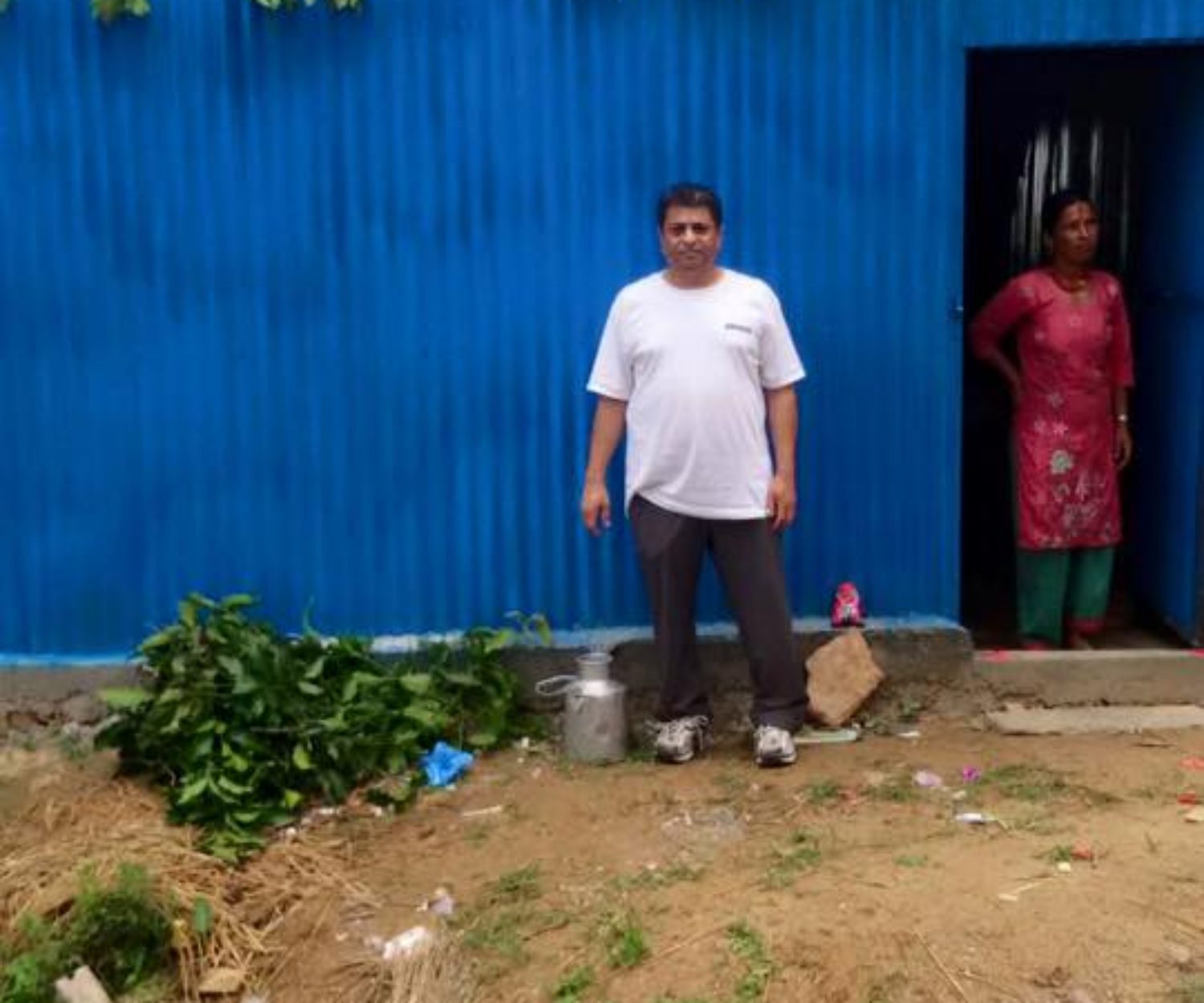 Indian man and woman standing in front of their blue home