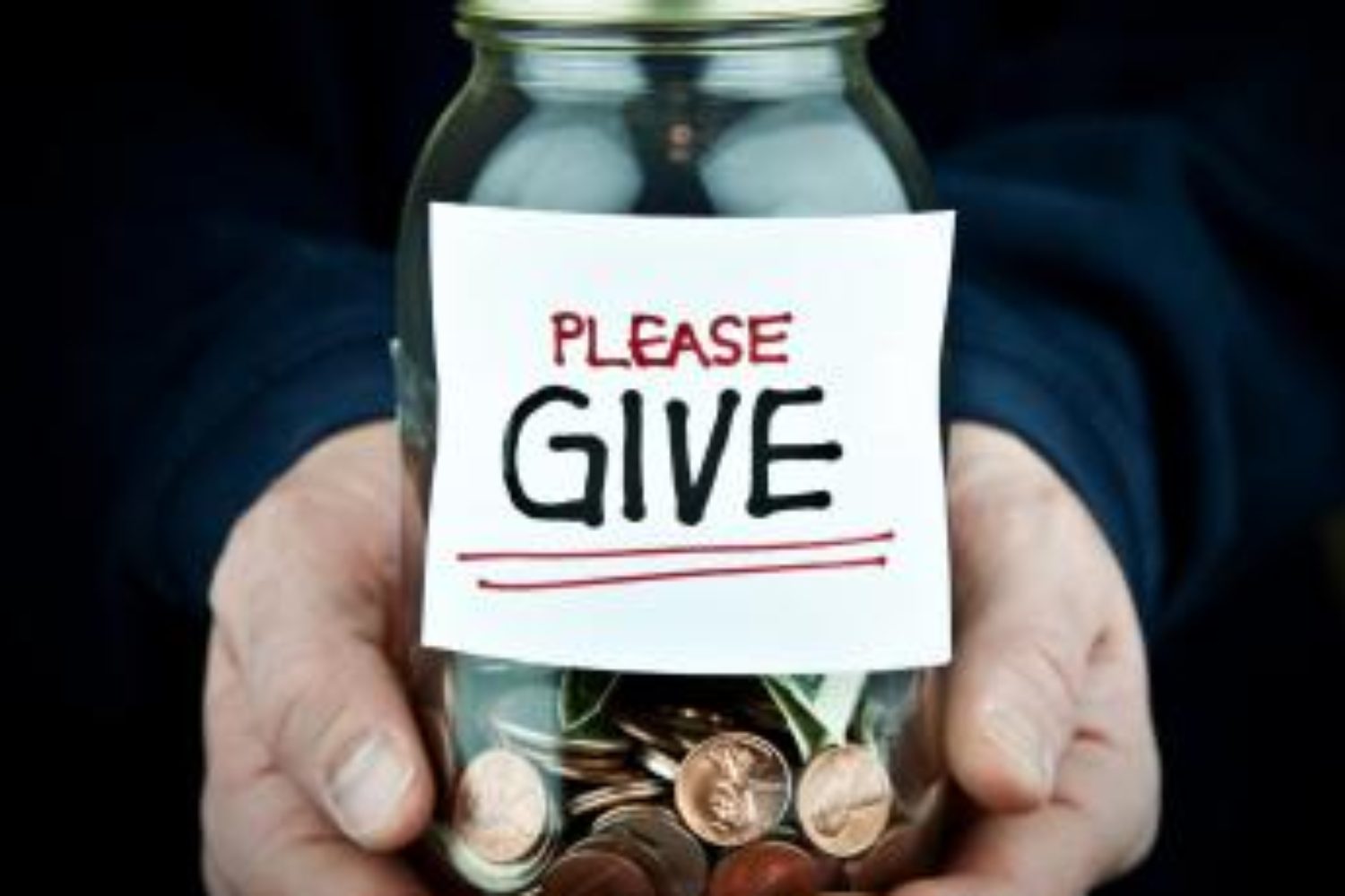 Hands holding a jar of change with a Please Give sign