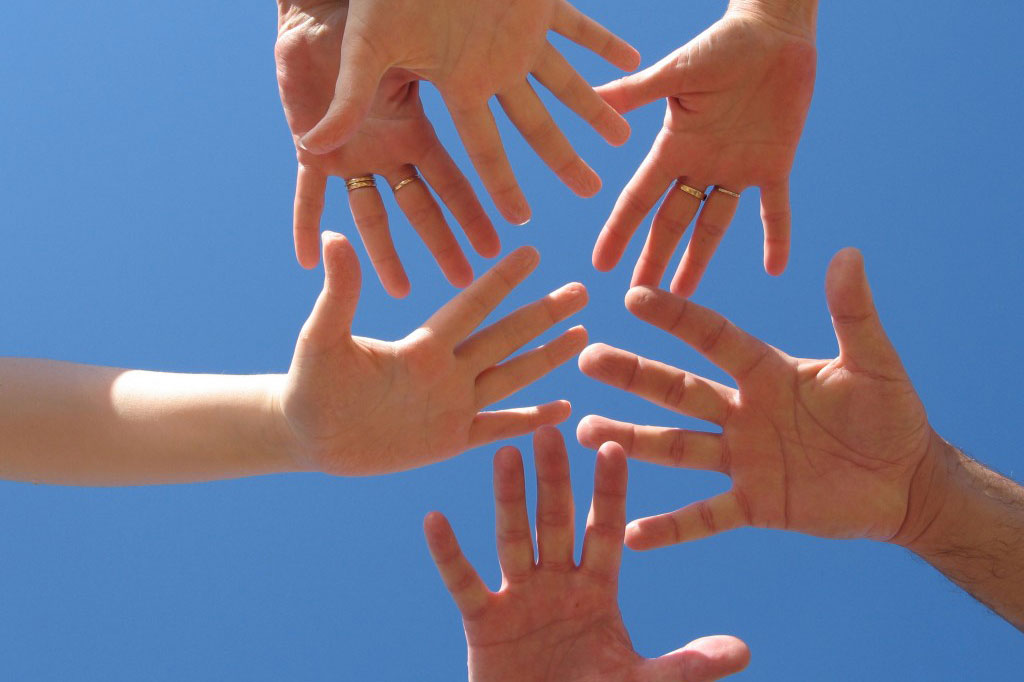6 hands reaching in a circle with blue background